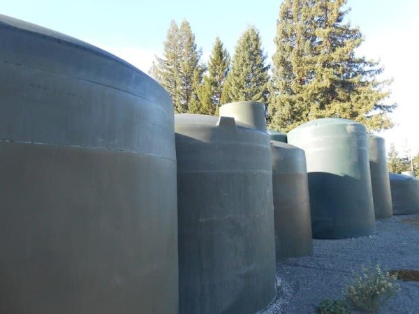 The image displays vertical polyethylene water storage tanks of various sizes.